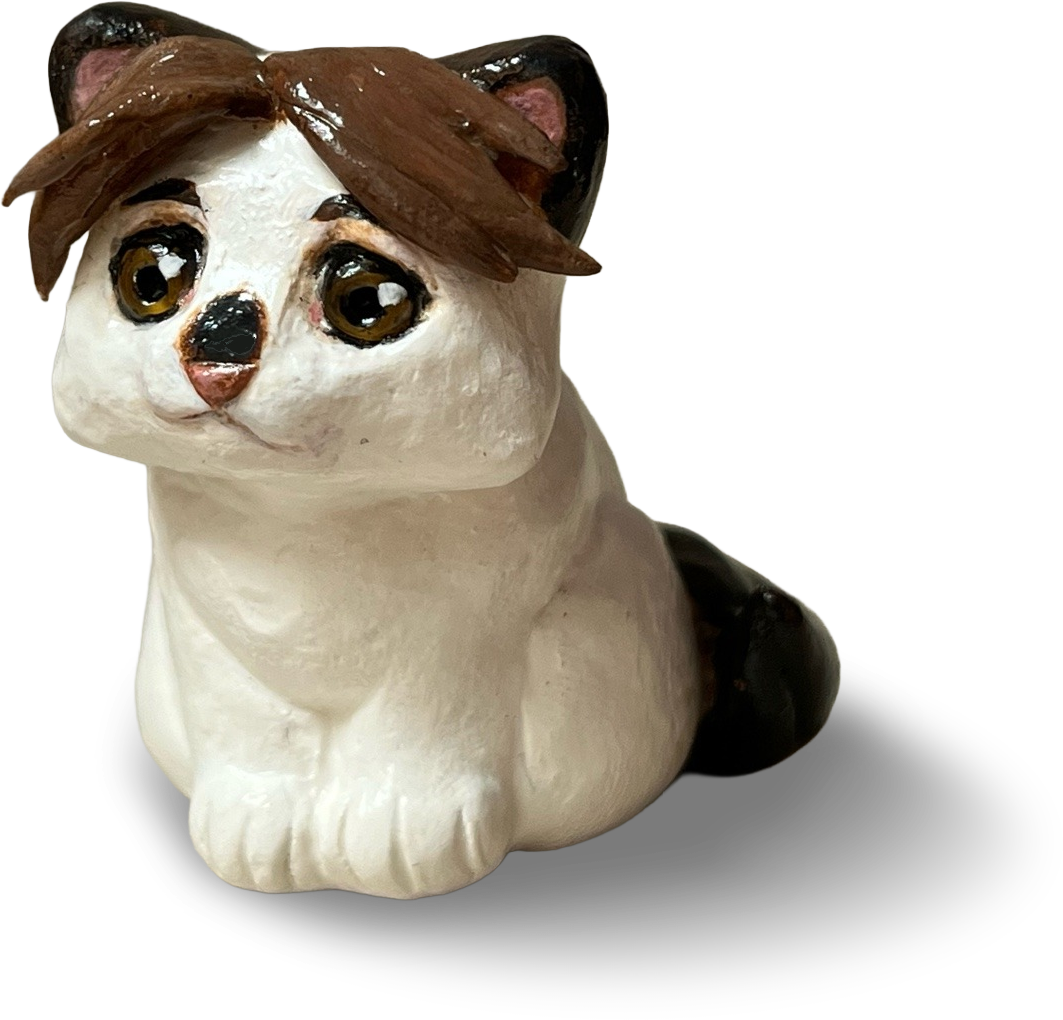 Clay figurine of a white and brown cat.